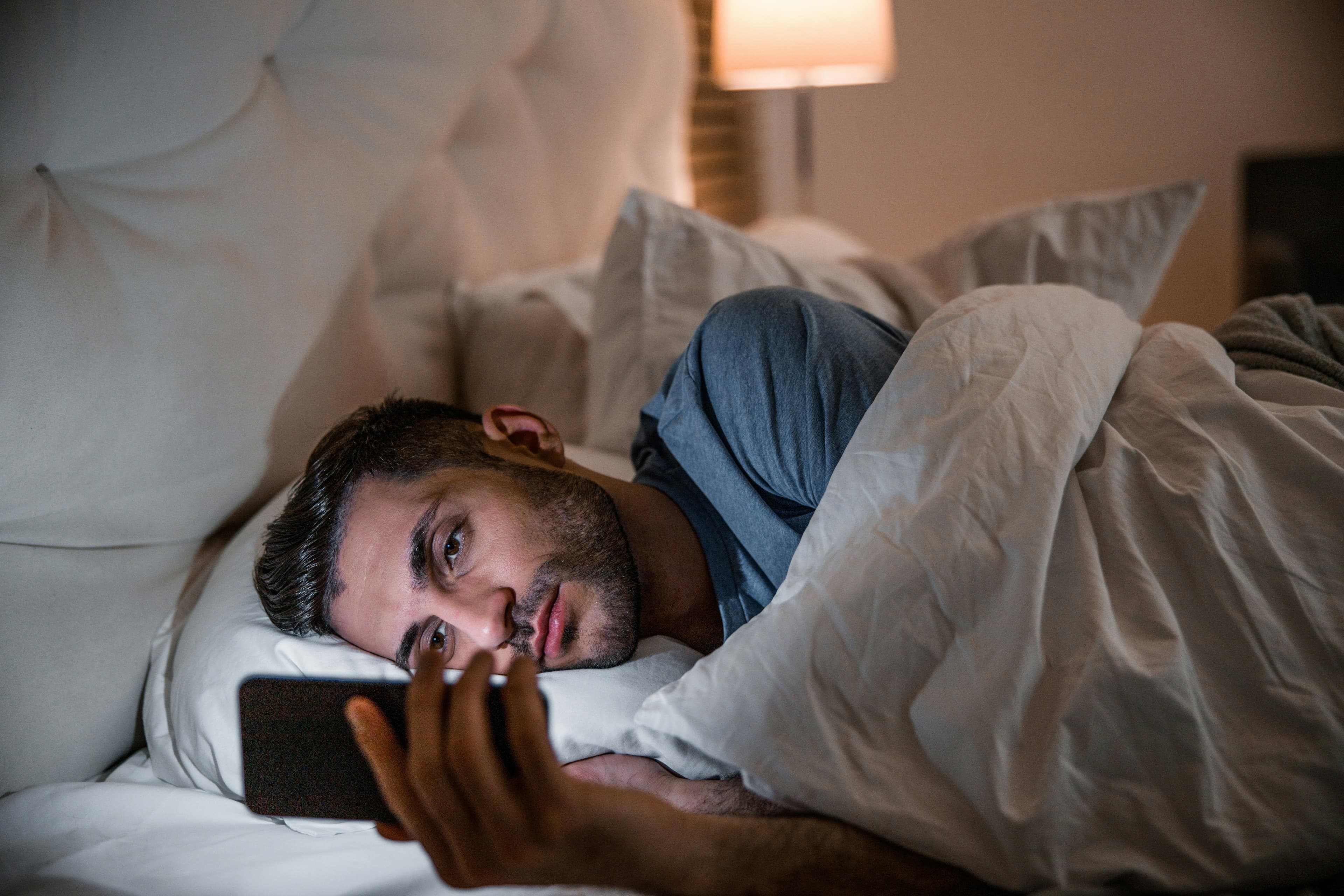 Man looking at his phone late at night, illustrating the secrecy and isolation of compulsive pornography use