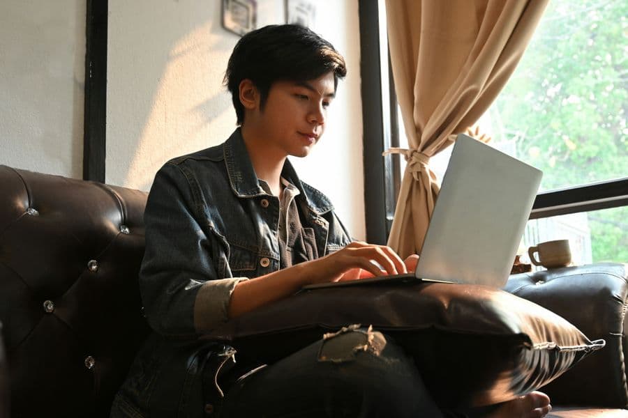 Young man sitting on couch with laptop